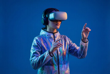 Young woman wearing virtual reality headset and silver futuristic jacket touching invisible interface. Concept for metaverse, gaming, cyberspace, and immersive digital technology experience.