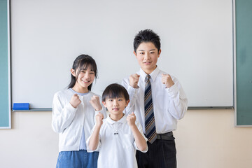 ホワイトボードの前でガッツポーズする3人の子ども