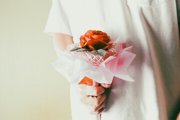 Person holding a red rose bouquet behind back, concept of romantic surprise, valentine's day gift, and secret love.