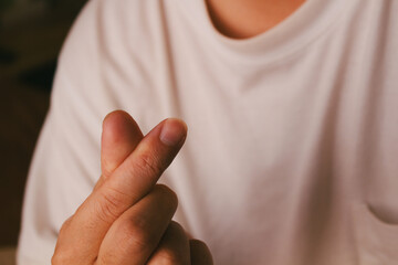 Close up of hand making mini heart sign with fingers over white t-shirt background, Korean style love symbol.