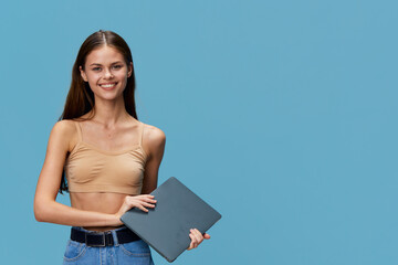 Obraz premium smiling young woman holding laptop, casual outfit, blue background, happy expression, technology, lifestyle concept