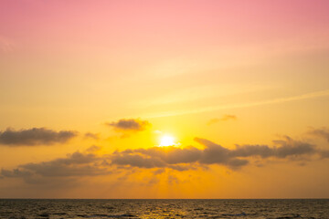 Fototapeta premium Nature sky breathtaking golden sunset over a calm ocean, with the entire sky and water bathed in brilliant shades of yellow and orange. Streaky clouds enhance the dramatic display of light 