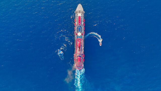 Kusadasi, Turkey. Top down a cruise ship maneuvering in the bay. Shot shows swimming pools, sun lounges, and funnels against the water. Aerial View