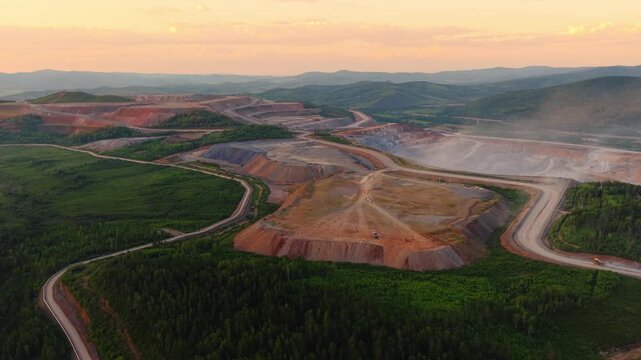 Aerial view of expansive open pit mine at dusk with surrounding landscape. Industry mining gold ore or platinum.