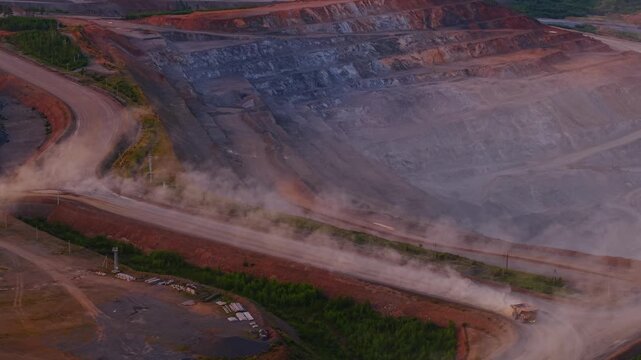 Big yellow truck moving of open pit mine for gold or iron ore in industry landscape, sunset time Aerial view.