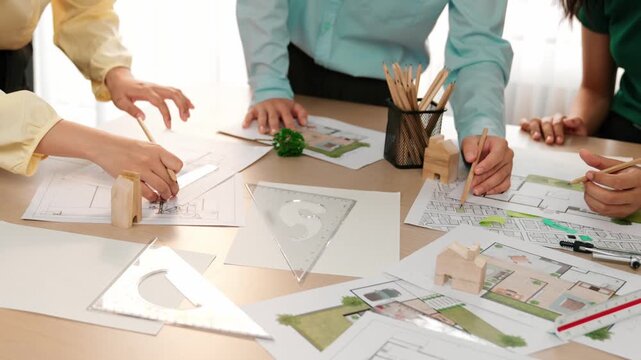A video of architect use measurement tools and pencil to measure blueprint. Architect design house construction on a table at studio, with architectural plan scattered around. Focus hand. Delineation.