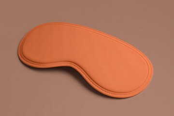 Fototapeta premium A single orange shaped eye mask for sleep or relaxation on a brown background