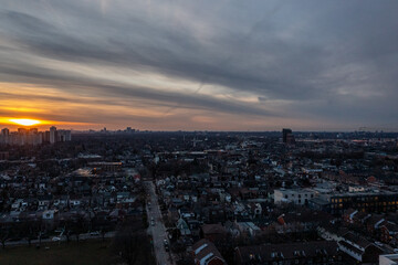 Naklejka premium Cityscape view over residential housing and urban sprawl in toronto, ontario, canada, with a dramatic cloudscape catching the golden hour light during sunset