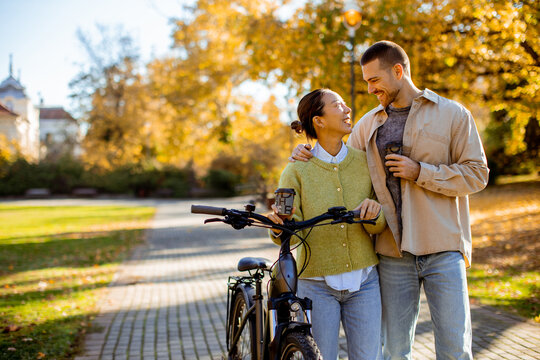 Couple enjoys a sunny autumn day while biking in a beautiful park filled with fall colors