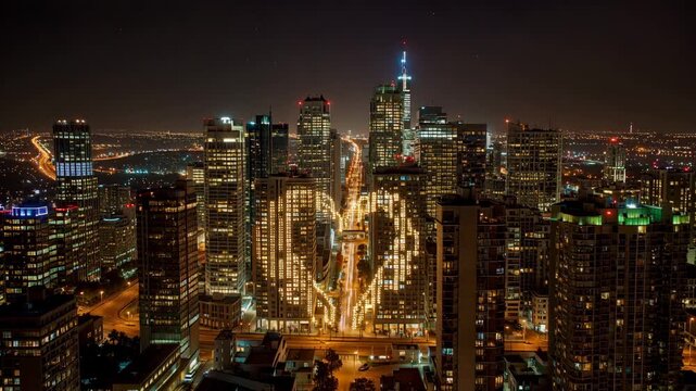 A city skyline at night where windows gradually light up to form a glowing heart shape