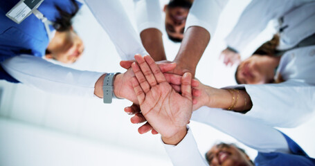 Doctors, team and stack hands in circle at hospital with support, motivation and celebration for goals. People, medical professional and group with low angle, synergy or healthcare services at clinic