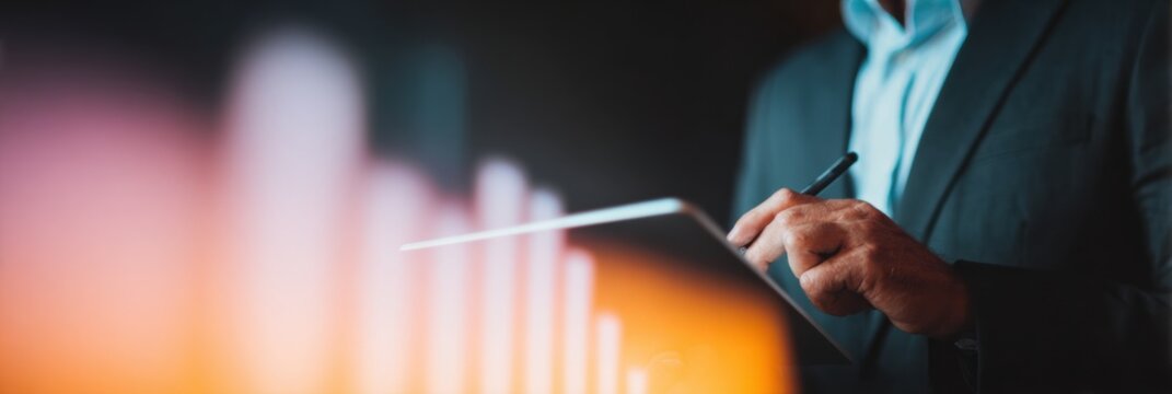 Businessman analyzing corporate growth on digital tablet with glowing virtual charts in background for financial data visualization and business process optimization - Powered by Adobe