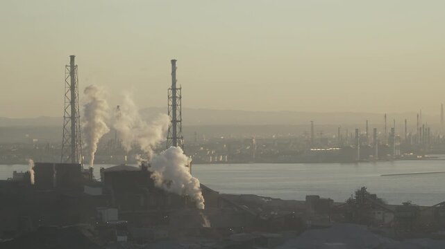 Wide view of an industrial port facility and factory complex by the sea.