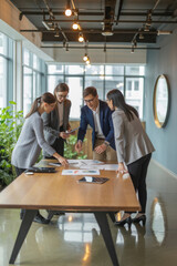 Diverse team of business analytic professionals reviewing statistic repots together, bending over table with papers, discussing marketing research results, developing strategy of growth. Vertical shot