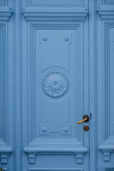 Classic light blue wooden door with ornate panels and gold handle detail