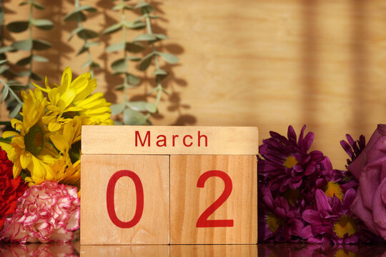 March 2nd. Wooden calendar with fresh flowers around it. Copy space.