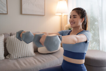 Young woman lifting dumbbells while exercising at home