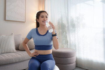 Asian woman drinking water after home workout