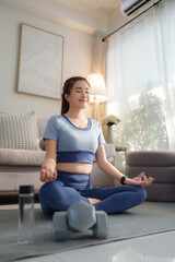 Young woman meditating in lotus pose at home