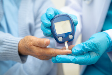 Asian doctor using digital glucose meter for check sample blood sugar level to treatment diabetes.