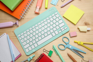 Composition with computer keyboard and school supplies on wooden background, closeup