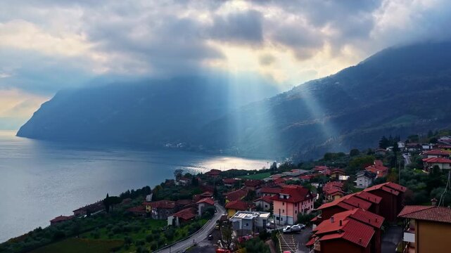 Rising drone shot on the shore of Lake Iseo as the sun breaks through the clouds.