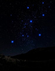 A dark night sky with stars and a mountain silhouette