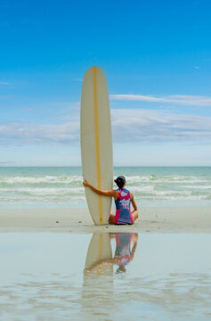 Asian play surf alone on the summer beach. Solo outdoor activity on holiday