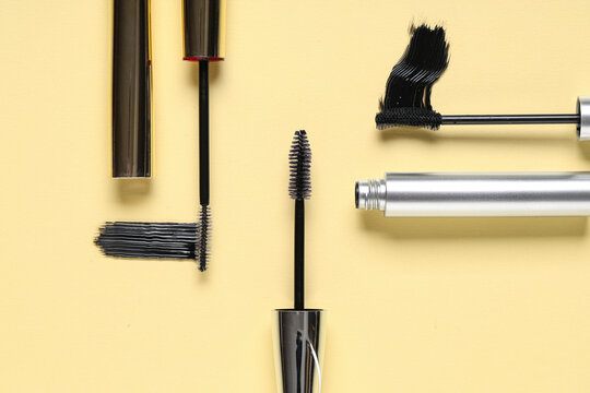 Black mascaras with smears on yellow background