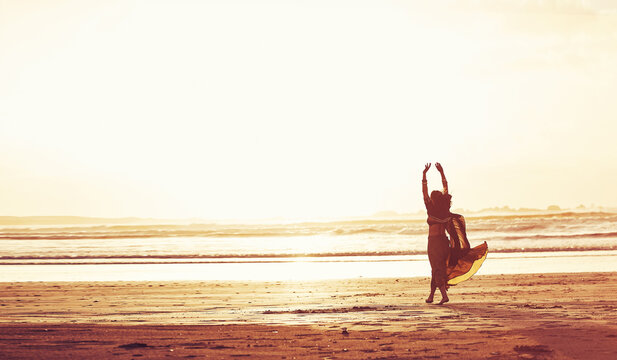 Woman, sunset and beach with freedom for travel, holiday or weekend vacation in nature. Female person, back view or hands in air with space or waves for outdoor getaway or trip on ocean coast by sea