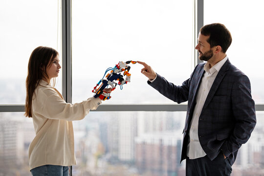 Teenage girl and man engineer interacting with hydraulic arm. STEAM