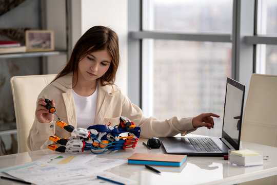 student is holding and examining a robotic arm. STEAM education.