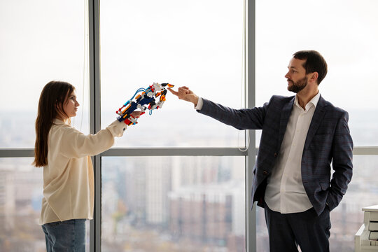 Teenage girl and man engineer interacting with hydraulic arm. STEAM