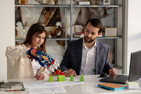 Young woman learning to maneuver hydraulic arm with man mentor.