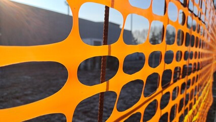 Construction site open building construction. Orange plastic mesh emergency fence, to separate construction site areas with the road.