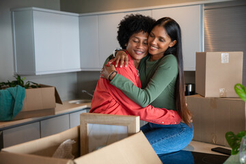 African american and indian couple hugging on kitchen island with moving boxes, picture frame © wavebreak3