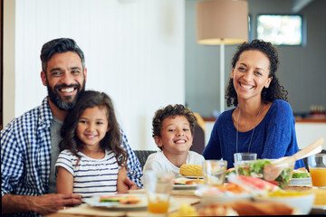 Fototapeta premium Portrait, happy family and children at dining table with food, nutrition and care for bonding together. Parents, kids and smile in home with lunch, healthy meal and love for connection on weekend.
