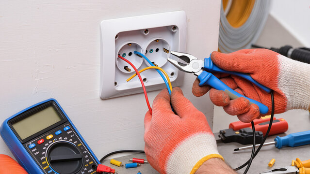 electrician installing electrical outlet, Expert performs maintenance work, Specialist handles electrical parts, Work area stays organized, Using hand tools, Gloves protect hands, Safety is first