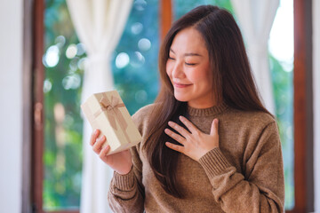 Portrait image of a surprised woman receiving and looking at a present box at home