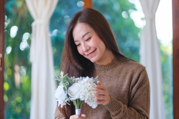 Portrait image of a beautiful woman holding a flower bouquet at home