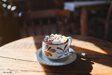 Closeup image of a cup of hot chocolate with marshmallow on wooden table