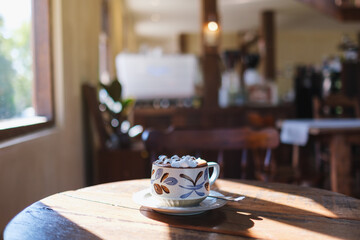 Closeup image of a cup of hot chocolate with marshmallow on wooden table
