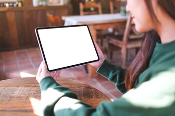 Mockup image of a woman holding digital tablet with blank white desktop screen in cafe