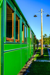 Green train car sits on tracks under bright sunlight in a rail yard, showcasing its vintage design and sturdy construction