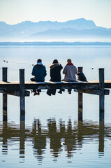 wooden pier with mountains in the distance, reflecting on calm water in the early morning light