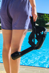 Close-Up of a Woman Holding a Snorkeling Mask Against Background a Sparkling Pool, Ready for an Exciting Underwater Adventure.