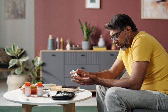 Man checking blood sugar with glucometer at home healthcare setting