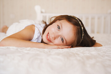 Fototapeta premium Girl smiles while lying on a bed in a bright room