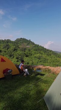 Asian women camping alone with mountain view. Solo outdoor activity and journey lifestyle on holiday.