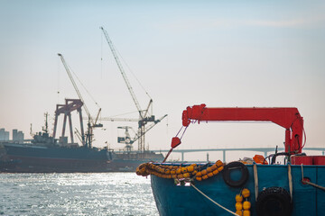 A commercial fishing boat rests in the industrial port of Busan, South Korea, where heavy cargo...